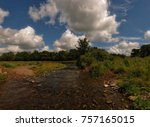Trout stream among fields with dramatic clouds above