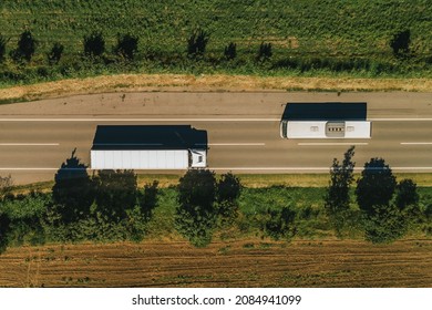 Truck and bus on the road from drone pov, top view of two vehicles passing by each other on roadway through countryside