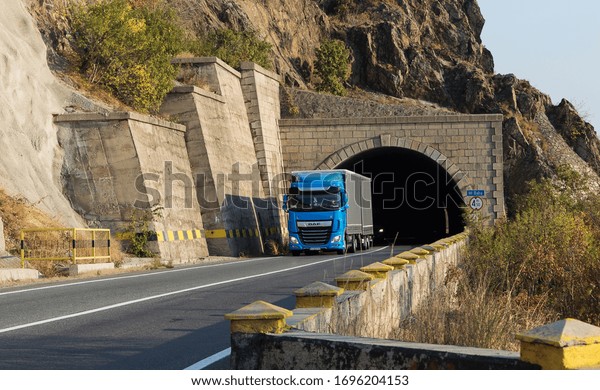 Truck carrying freights or goods on a mountain road,\
at the exit of a tunnel. A beautiful spring day in traffic. This is\
a DAF truck.  The vehicle is blue. Romania, Orsova,  April 5,\
2020