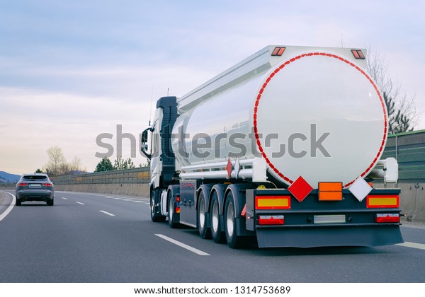 Truck with cistern on road. Trucker on highway.\
Lorry doing logistics work. Semi trailer with driver. Big cargo\
car. Freight delivery. Transport export industry. Container with\
loaded goods