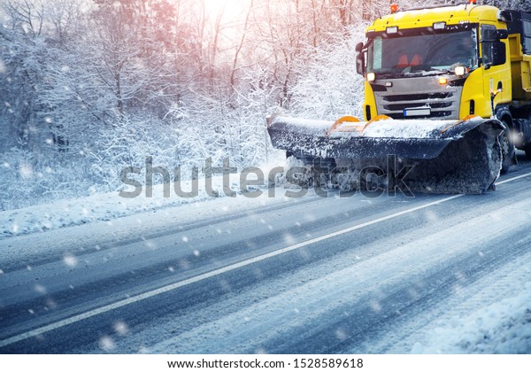 Truck cleaning\
on winter road covered with\
snow