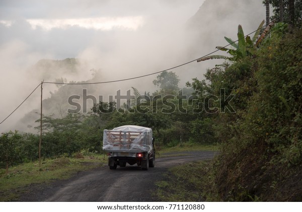 Truck collecting routes on rural route between\
hills in Colombia.