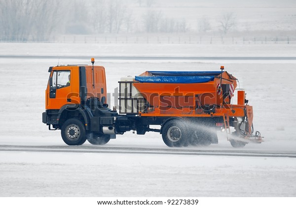 Truck deicing a road in\
winter