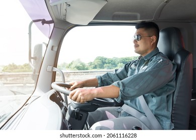 Truck Driver Asian Young Man Wearing Sunglasses Fasten Seat Belt For Safety While Driving. Smile Confidence Positive Optimistic Professional Male Owner Business Long Transport Delivery Semi-truck.