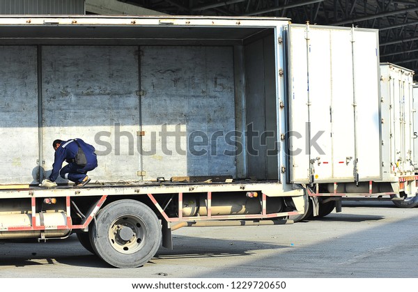 Truck\
driver cleaning freight compartment of a\
truck.