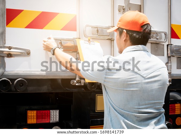 Truck driver\
is closing the container door. Steel door security lock of a truck,\
freight industry logistics,\
transport