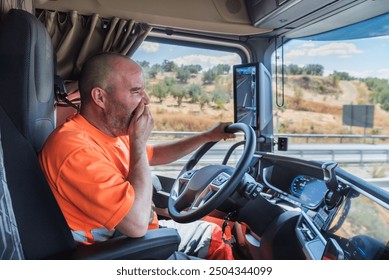 Truck driver driving the truck on the highway and yawning in a clear gesture of tiredness and fatigue at the wheel. - Powered by Shutterstock