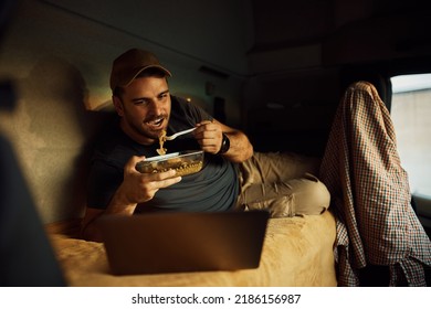 Truck Driver Eating Lunch While Using Laptop In A Cabin.