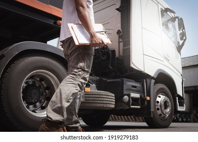 Truck Driver Holding Clipboard Is Checking The Truck's Safety Maintenance Checklist. Mechanic Repairman Shop. Inspection Of Semi Truck Wheels Tires.Shipping Cargo Freight Truck Transport Logistics.