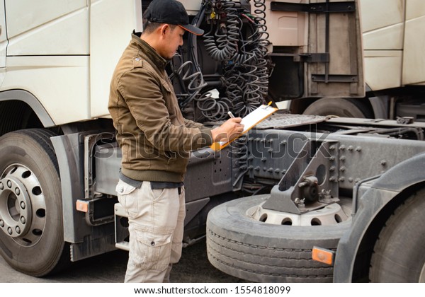 Truck driver holding clipboard inspecting\
safety checklist program before driving a\
truck
