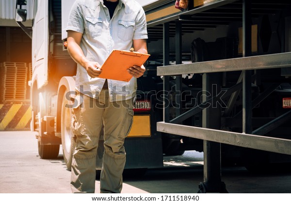 truck driver holding clipboard inspecting\
safety checklist semi truck, vehicle maintenance daily checklist,\
road freight industry\
logistics.