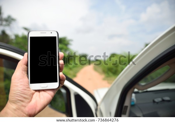 Truck driver holding smart phone with blank\
screen on dirt road into the wilderness, GPRS navigation or finding\
phone signal conceptual