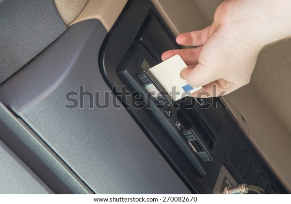 Truck driver is inserting tachograph card to the\
device inside the truck\
cab.