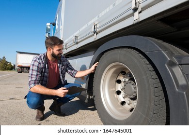 Truck driver inspecting tires and checking depth of tire tread for safe ride. Controlling vehicle before transportation service.