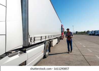 Truck driver inspecting vehicle, trailer and tires before driving. Truck preparation before ride. Transportation services.