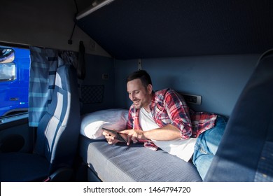 Truck Driver Lying On Bed In His Cabin Communicating With His Family Via Tablet Computer. People Separated From Their Families.