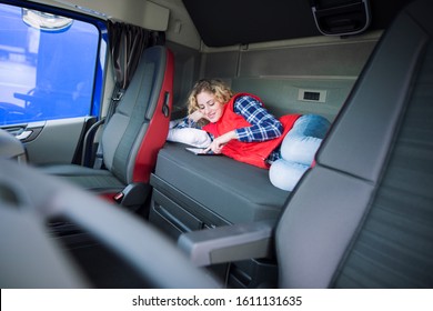 Truck Driver Lying On Bed In His Cabin Communicating With His Family Via Tablet Computer. People Separated From Their Families. Trucker Lifestyle.