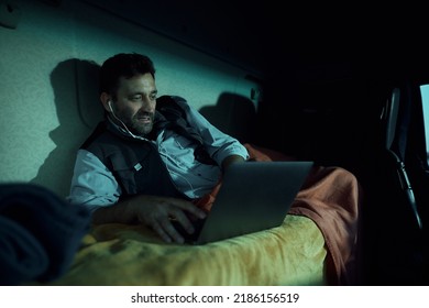 Truck Driver Making Video Call While Using Laptop In His Cabin At Night.