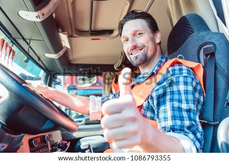 Truck driver man sitting in cabin giving thumbs-up 