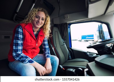 Truck Driver Occupation. Female Trucker Sitting In Truck Cabin And Smiling. Woman At Work. Transportation Services.