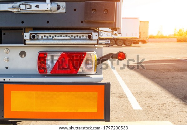 Truck\
driver semitrailer rear view, warning lights and long length signs\
on the trailer. Concept of safety and recreation at truck parking\
lots, sunset, copy space for text,\
commercial
