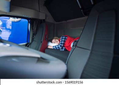 Truck Driver Sleeping On Bed Inside Truck Cabin Interior. Trucker Lifestyle And People Sleeping At Job.