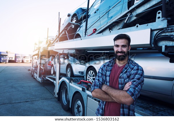 Truck driver transporting cars.
In background truck trailer with cars. Transportation
service.