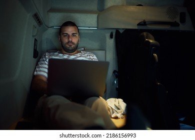 Truck Driver Using Laptop While Resting In A Cabin At Night. Copy Space.