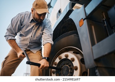 Truck Driver Using Socket Wrench While Changing Tire On The Road.