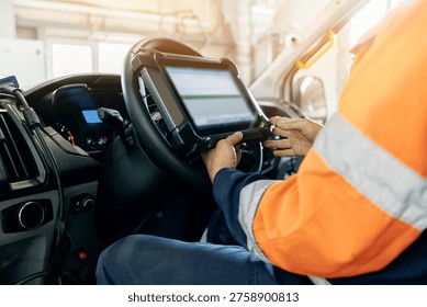 Truck driver using tablet while seated in vehicle cab during shift.