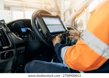 Truck driver using tablet while seated in vehicle cab during shift.
