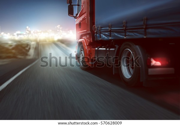 Truck drives on a country road with bokeh lights\
in the distance