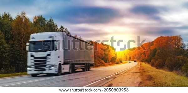 a truck is driving along the\
highway at sunset, a cargo transportation\
concept