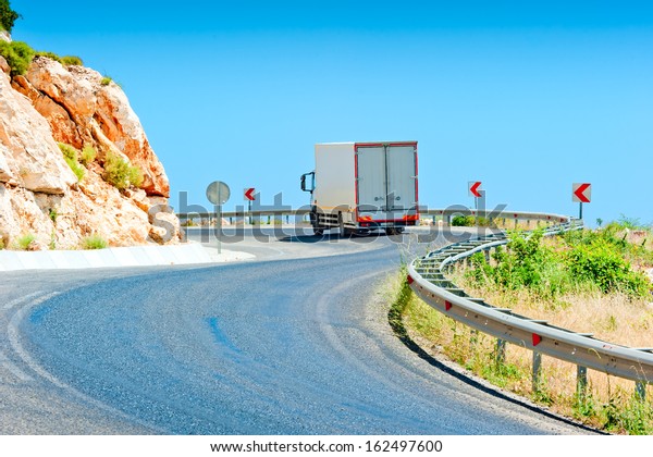 truck driving\
on a mountain road on a sunny\
day