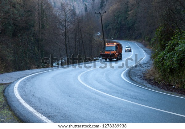 Truck driving on a mountain s-curve road in the\
afternoon. Two lane curvy\
road.