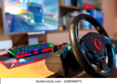 Truck Driving Simulator Steering Wheel On Focus In Front Of A Computer With Glowing Keyboard, Shallow Depth Of Field, Copy Space.