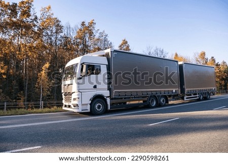 Truck is driving through the forest in autumn. Car transport . T