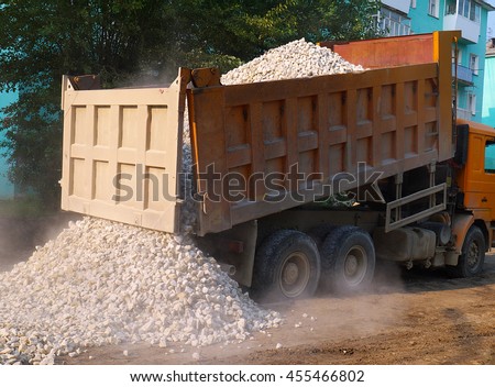 Truck dumping gravel on street roadway reconstruction site.