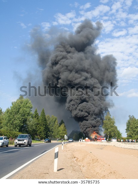 truck in fire with\
black smoke on the road