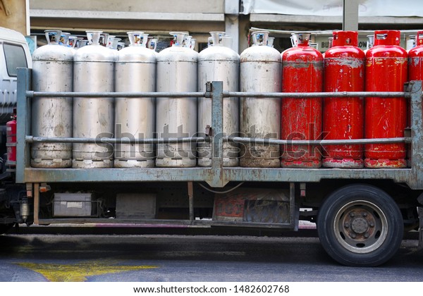 Truck with gas cylinders on the road.\
Many red and gray gas cylinders transported in\
car.