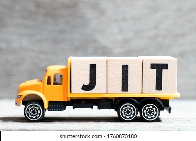 Truck hold letter block in word JIT (abbreviation of just in time)  on wood background