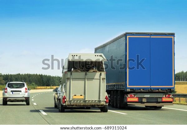 Truck and\
horse trailer on the road in\
Switzerland.