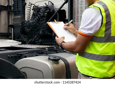 Truck Inspection And Safety. Truck Driver Writing  On Clipboard With Checking Truck Fuel Tank.