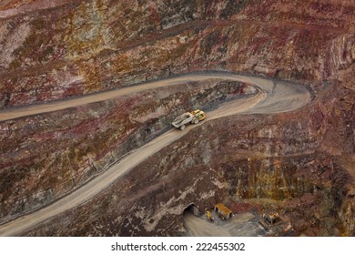Truck leaves hole in ground and drives along a winding path inside an open cast mine in New South Wales, Australia. 