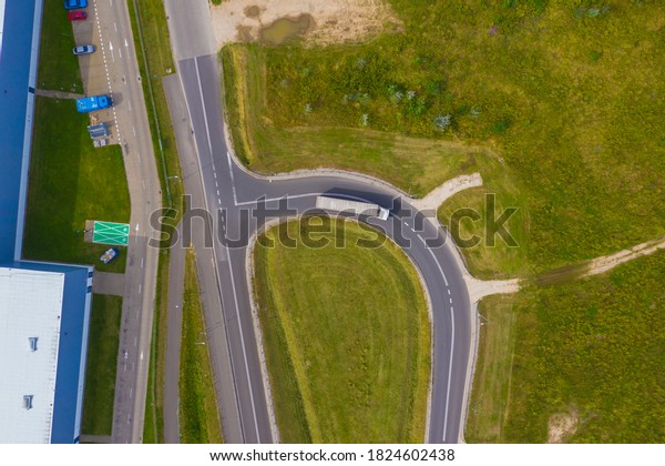 Truck logistic aerial.\
Trucks motion by the highway intersection road between fields. View\
from drone.