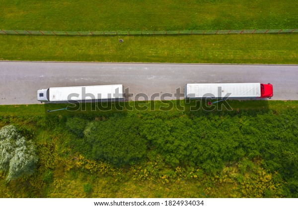 Truck logistic aerial. Two trucks motion by\
the road between fields. View from\
drone.