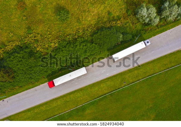Truck logistic aerial. Two trucks motion by\
the road between fields. View from\
drone.