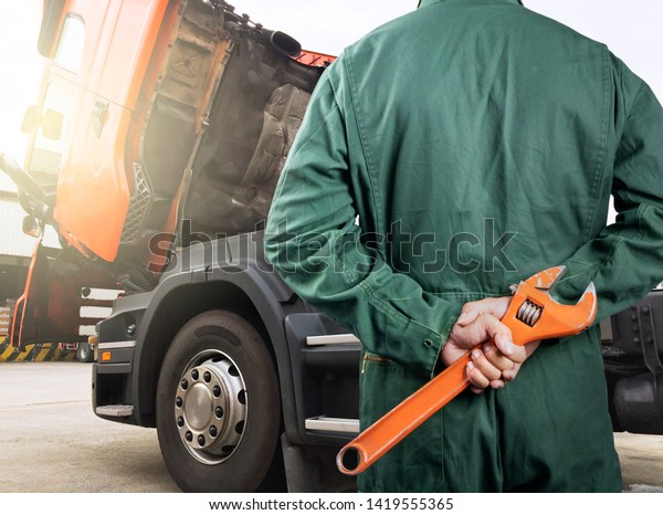 truck maintenance and\
repairing. professional auto mechanic holding large wrench\
repairing the truck\
engine.
