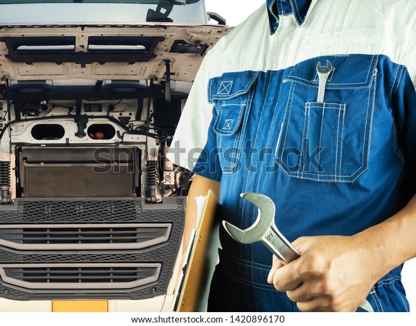 Truck maintenance and repairing. Professional\
auto technician holding wrench and clipboard with semi truck open\
the engine for repairing.