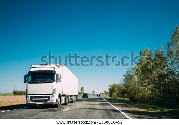 Truck In Motion On Country\
Road. Tractor Unit, Prime Mover, Traction Unit In Motion On\
Countryside Road In Europe. Business Transportation And Trucking\
Industry Concept